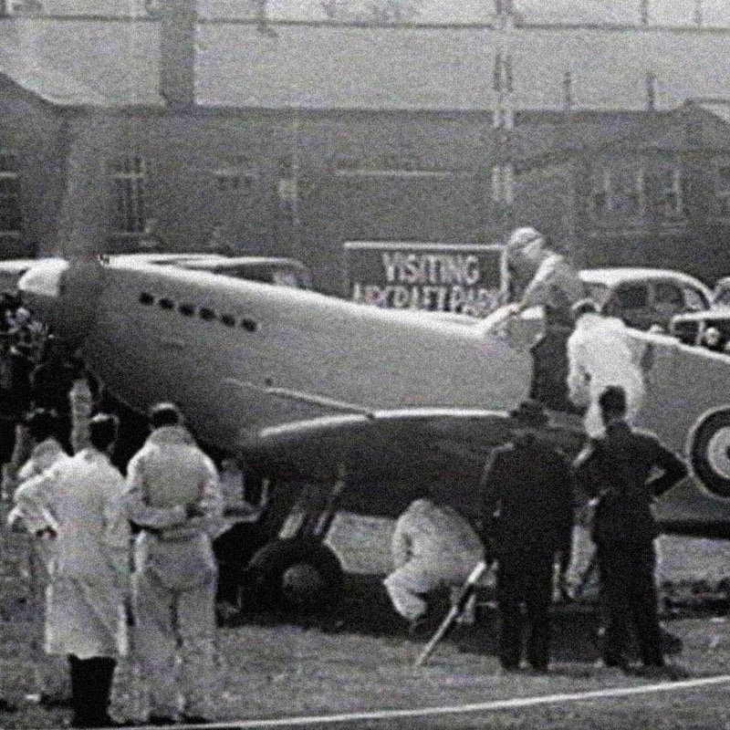 Black and white picture of men standing around a spitfire
