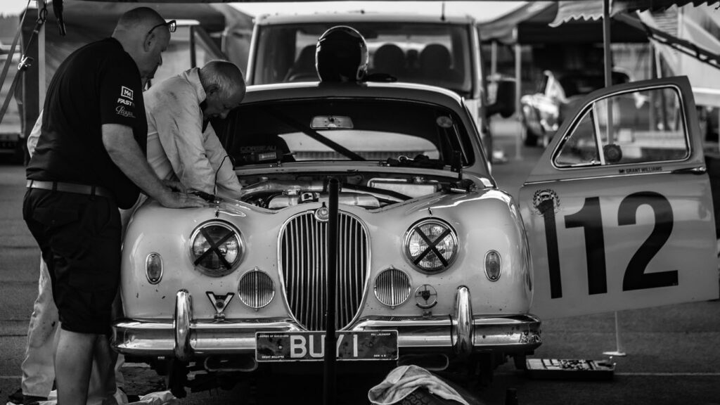 Black and white picture of two men working on vintage jaguar car engine